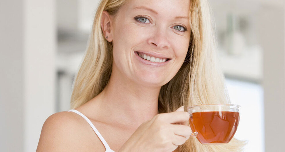 A woman holding up a cup of tea.
