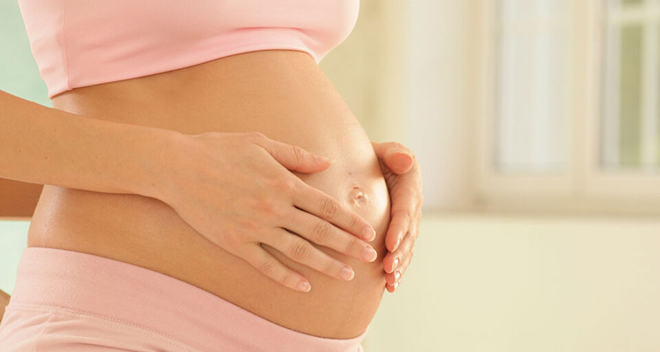 A pregnant woman placing her hands on her stomach.